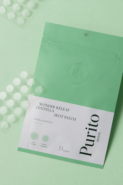 Close up of both sealed and opened Purito's Wonder Releaf Centella Spot Patches against a green background. Available for purchase at Sinless Skincare.