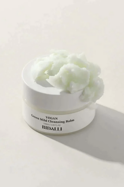 Texture shot of Bidalli's Green Mild Cleansing Balm spread on top of its closed jar, against a light grey background.