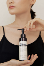 Load image into Gallery viewer, Woman in black top holding a bottle of Klairs&#39; Gentle Deep Black Cleansing Oil in front of her chest.
