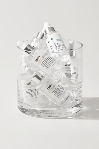 Tall glass bowl filled with bottles of Klairs' Freshly Juiced Vitamin Drop against a light grey background.