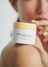 Load image into Gallery viewer, Woman holding jar of Ondo Beauty&#39;s Multiacids &amp; Papaya Cleansing Balm on her bare shoulder. Her face is blurred out in the background.
