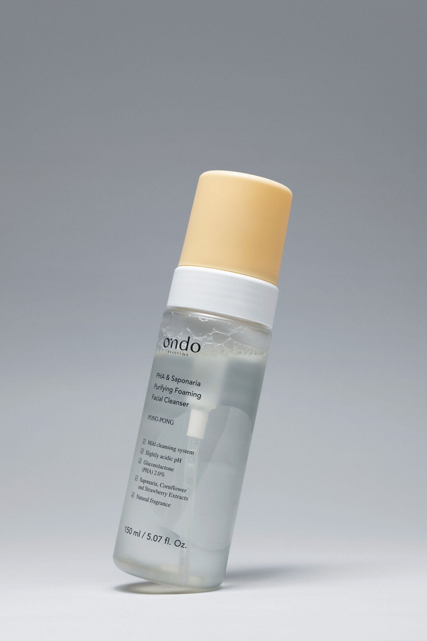 A bottle of Ondo Beauty 36.5 PHA & Saponaria Foaming Cleanser against a grey background, leaning over slightly. Available for purchase at Sinless Skincare.