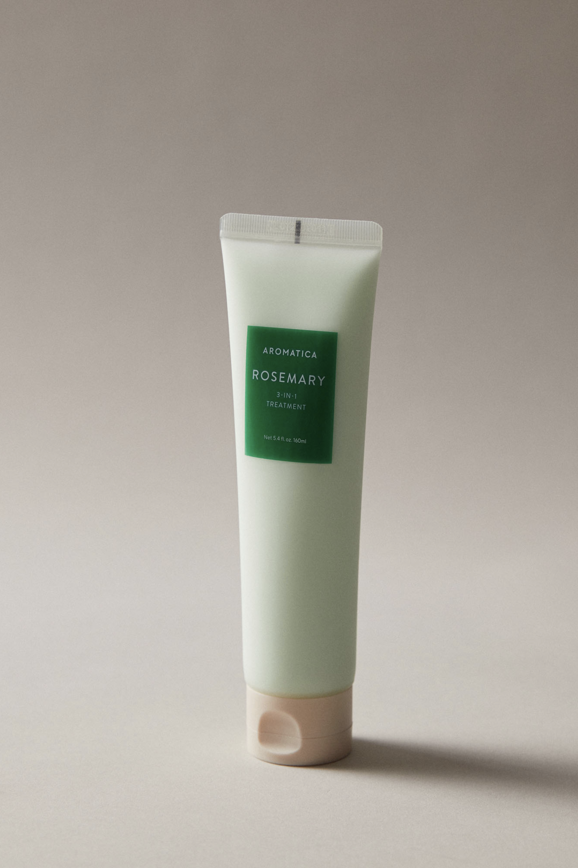 Bottle of Aromatica's Rosemary 3-in-1 Treatment against a soft grey background