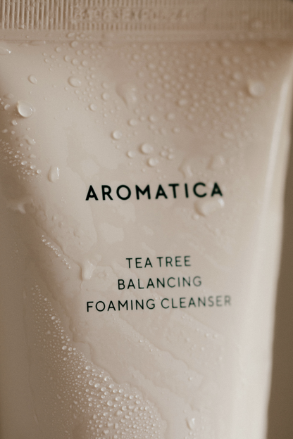 Close-up of the bottle's top from Aromatica's Tea Tree Balancing Cleanser, glistening with water droplets.