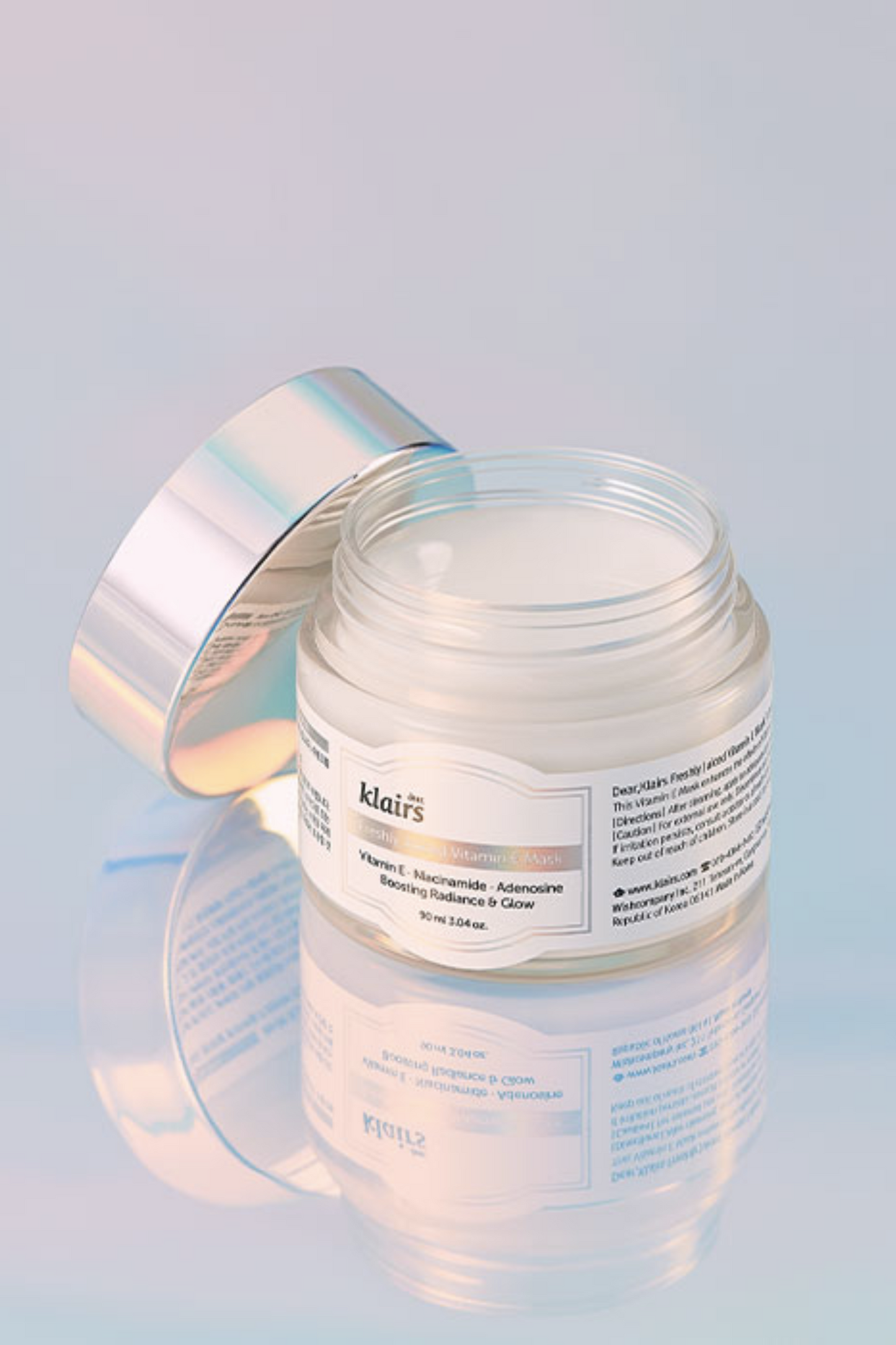 Open jar of Klairs' Freshly Juiced Vitamin E Mask against a shiny light blue background, with its reflection visible. Available for purchase at Sinless Skincare.