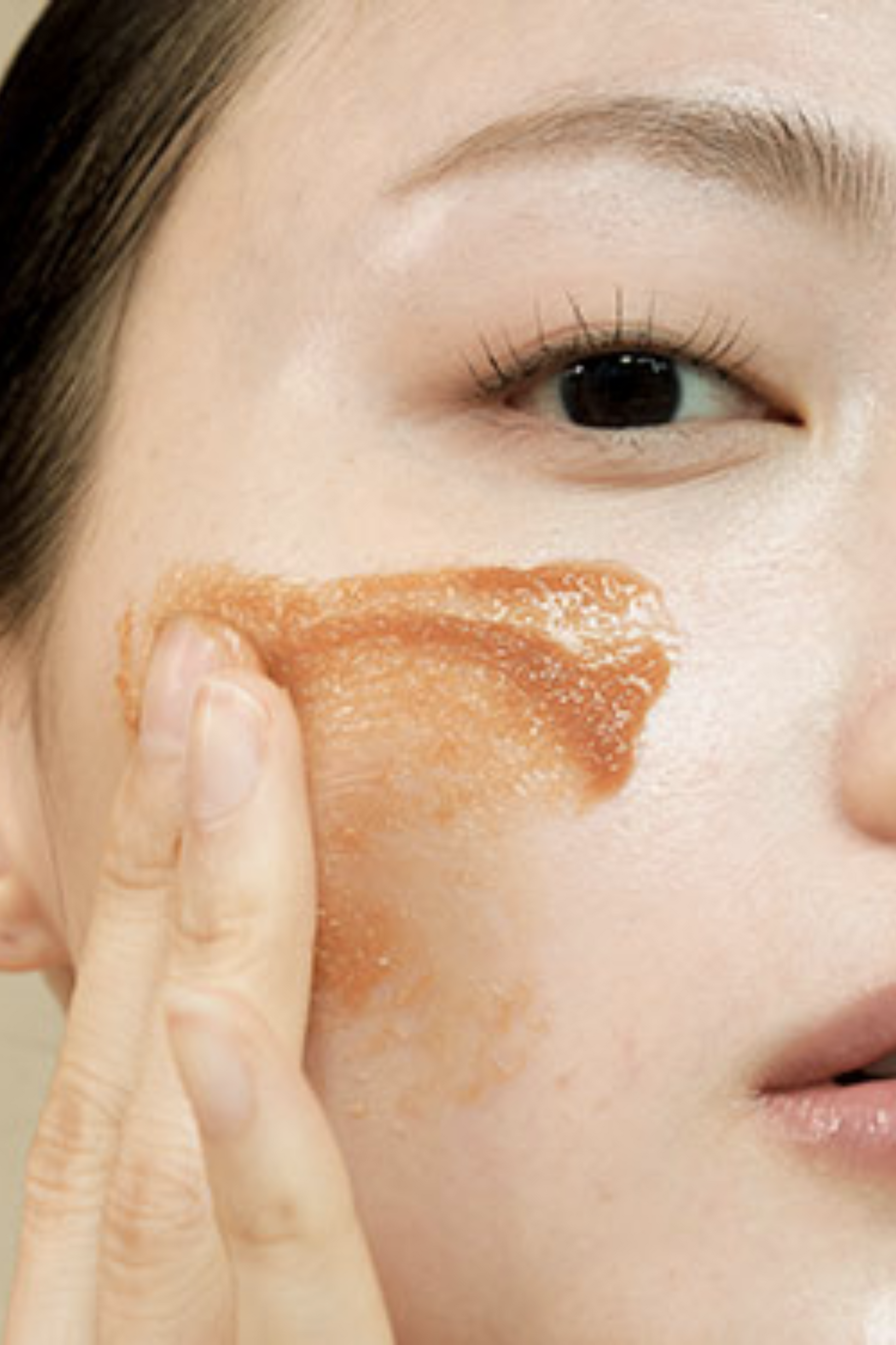 Close up of woman applying Klairs Gentle Black Sugar Facial Polish to her cheek.