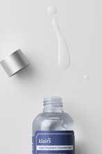 Load image into Gallery viewer, Bottle of Klairs Supple Preparation Unscented Toner with the cap off and some toner spilled in front of it. Only the top of the bottle is visible.
