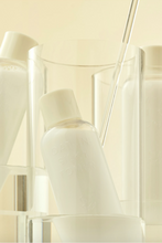 Lade das Bild in den Galerie-Viewer, Close up of a bottle of Purito&#39;s Oat-in Silky Toner inside a glass, with other bottles of product standing behind it, against a beige background. Available for purchase at Sinless Skincare.
