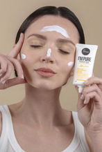 Lade das Bild in den Galerie-Viewer, Close up of a woman holding a tube of Suntique&#39;s I&#39;m Pure Perfect Cica sunscreen on the side of her face. She has visible streaks of product on her forehead, nose, and cheeks. She is standing against a beige background.
