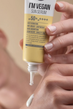 Lade das Bild in den Galerie-Viewer, Close up of woman&#39;s hands squeezing a tube of Suntique&#39;s I&#39;m Vegan Sun Serum sunscreen.
