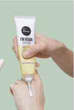 Lade das Bild in den Galerie-Viewer, Close up of sunscreen being squeezed out of tube onto woman&#39;s hand against a light green background. Suntique I&#39;m Vegan Sun Serum SPF
